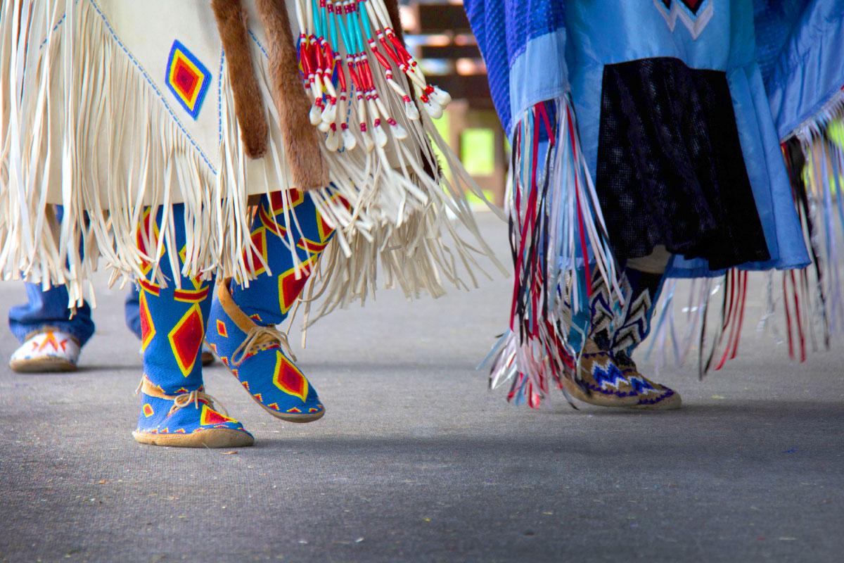 Two individuals in their traditional Native American moccasins dancing